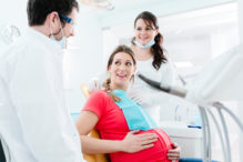 pregnant woman upright in dental chair - use caution but don't avoid the dentist while pregnant