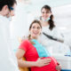 pregnant woman upright in dental chair - use caution but don't avoid the dentist while pregnant