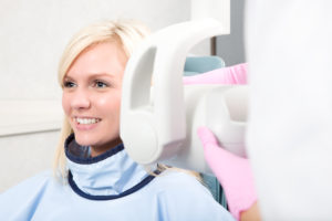 A Smiling woman getting her teeth x-rayed - while pregnant take extra precautions but don't avoid necessary dental care.