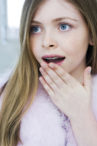 girl with braces with hand partially covering mouth